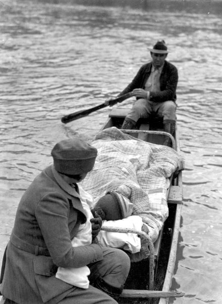 Local man transporting a sick mother to the hospital whilethe nurse stays close to the mother and holds her baby.