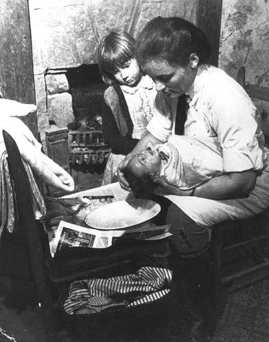 FNS nurse bathes a newborn baby while an older sibling observesthe process.